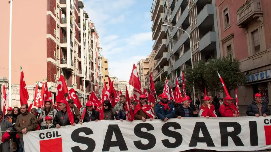 Manifestazione sindacale della CGIL a Sassari, con un folto gruppo di manifestanti che sfilano in strada tenendo uno striscione con la scritta 